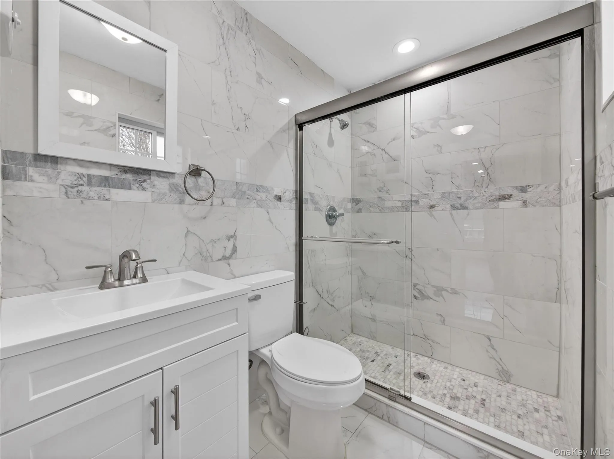 Bathroom featuring tile walls, vanity, a marble finish shower, and marble finish flooring Bathroom featuring tile walls, vanity, a marble finish shower, and marble finish flooring