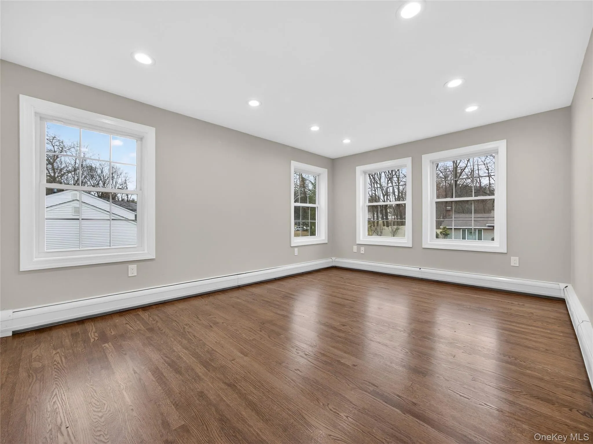 Empty room featuring a baseboard radiator, dark wood-type flooring, and recessed lighting Empty room featuring a baseboard radiator, dark wood-type flooring, and recessed lighting