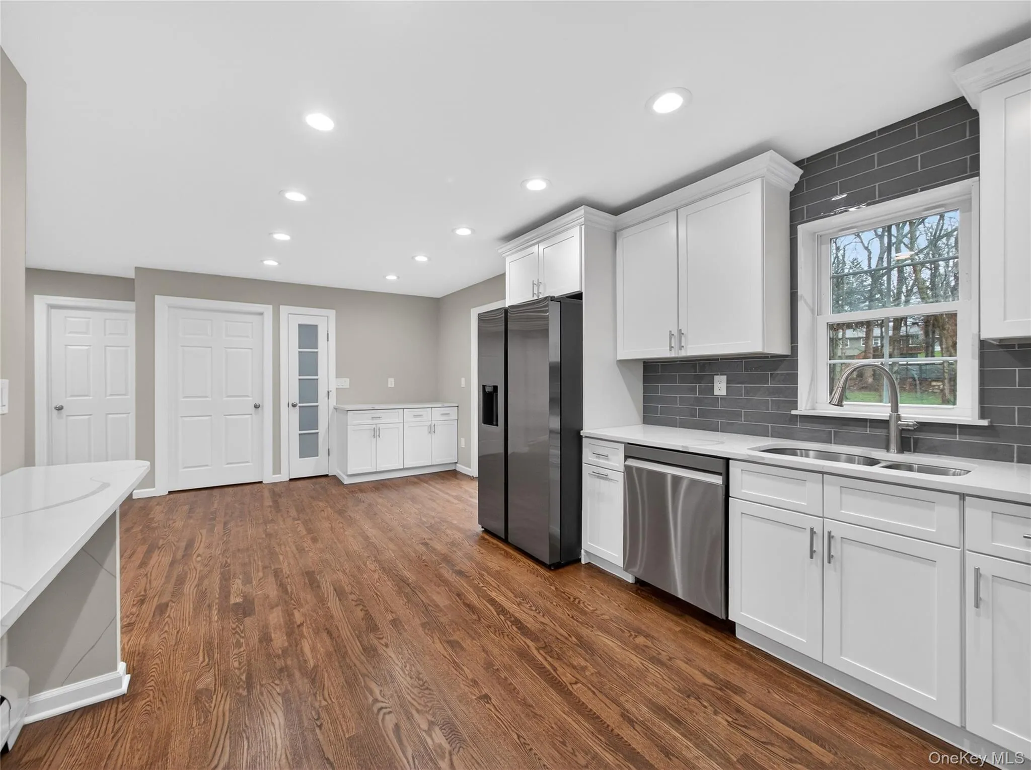 Kitchen featuring white cabinetry, stainless steel appliances, light stone counters, dark wood-style floors, and recessed lighting Kitchen featuring white cabinetry, stainless steel appliances, light stone counters, dark wood-style floors, and recessed lighting