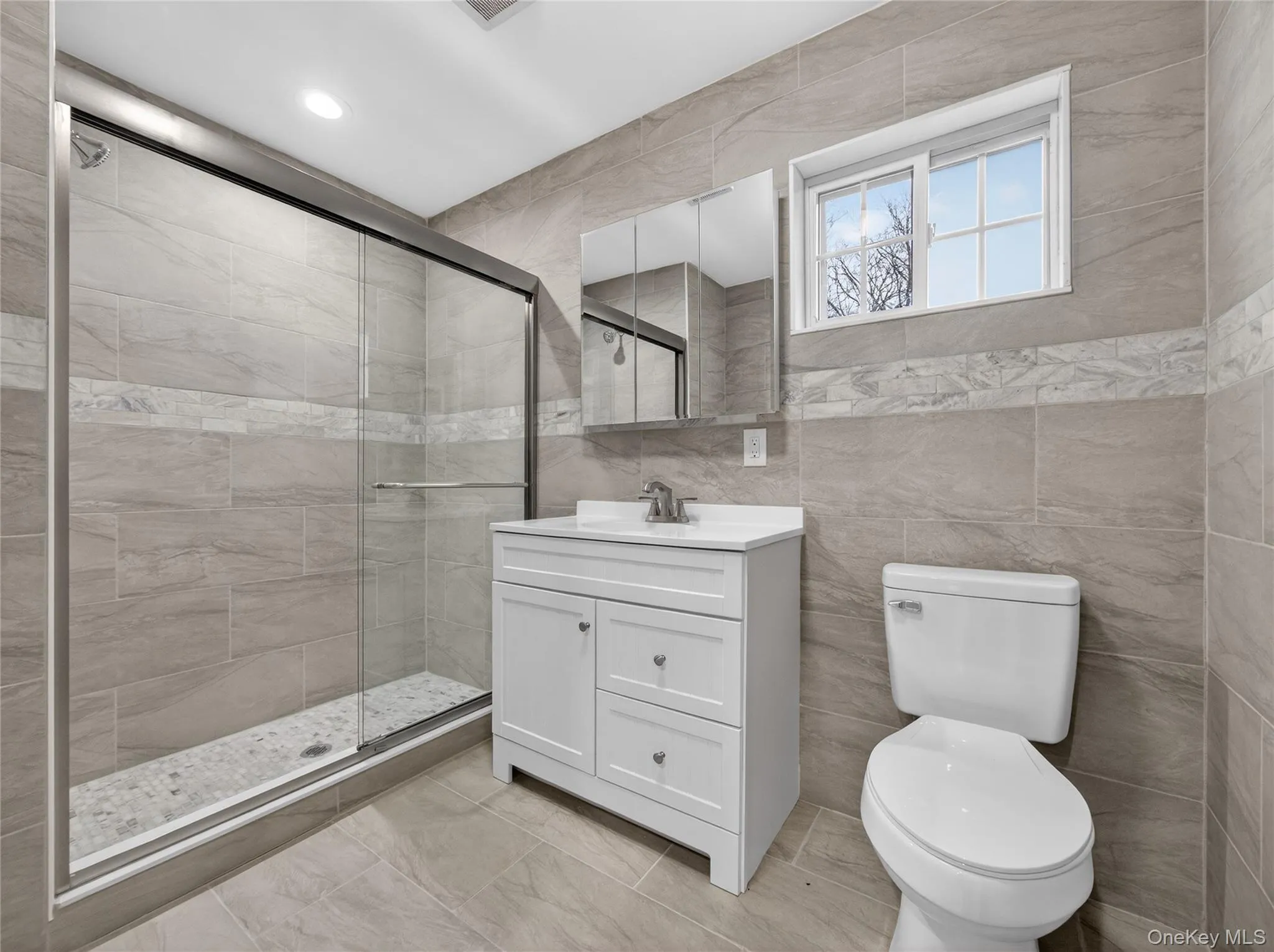 Bathroom featuring tile walls, vanity, and a stall shower Bathroom featuring tile walls, vanity, and a stall shower