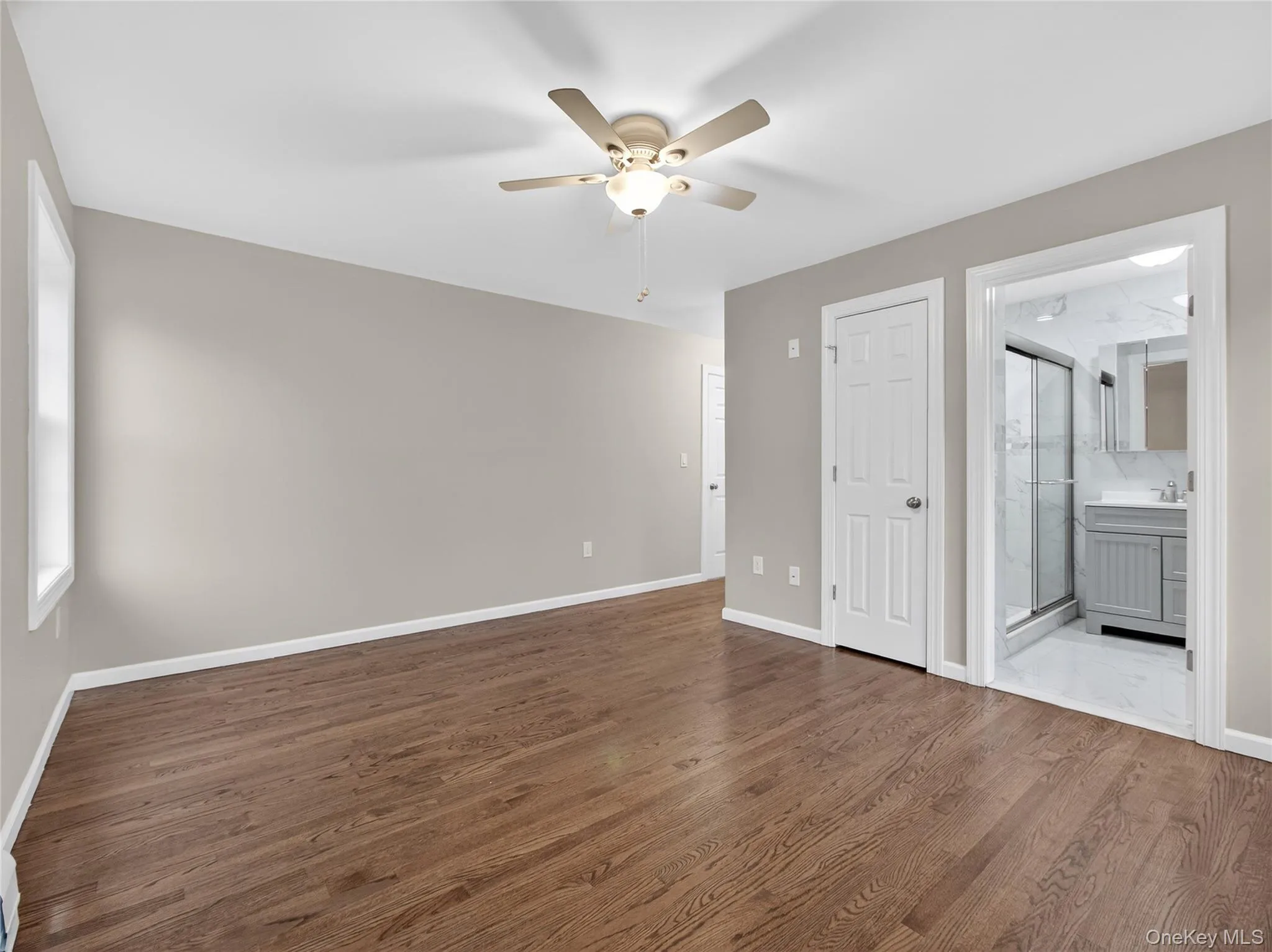 Unfurnished bedroom featuring dark wood-style flooring, a ceiling fan, and ensuite bathroom Unfurnished bedroom featuring dark wood-style flooring, a ceiling fan, and ensuite bathroom