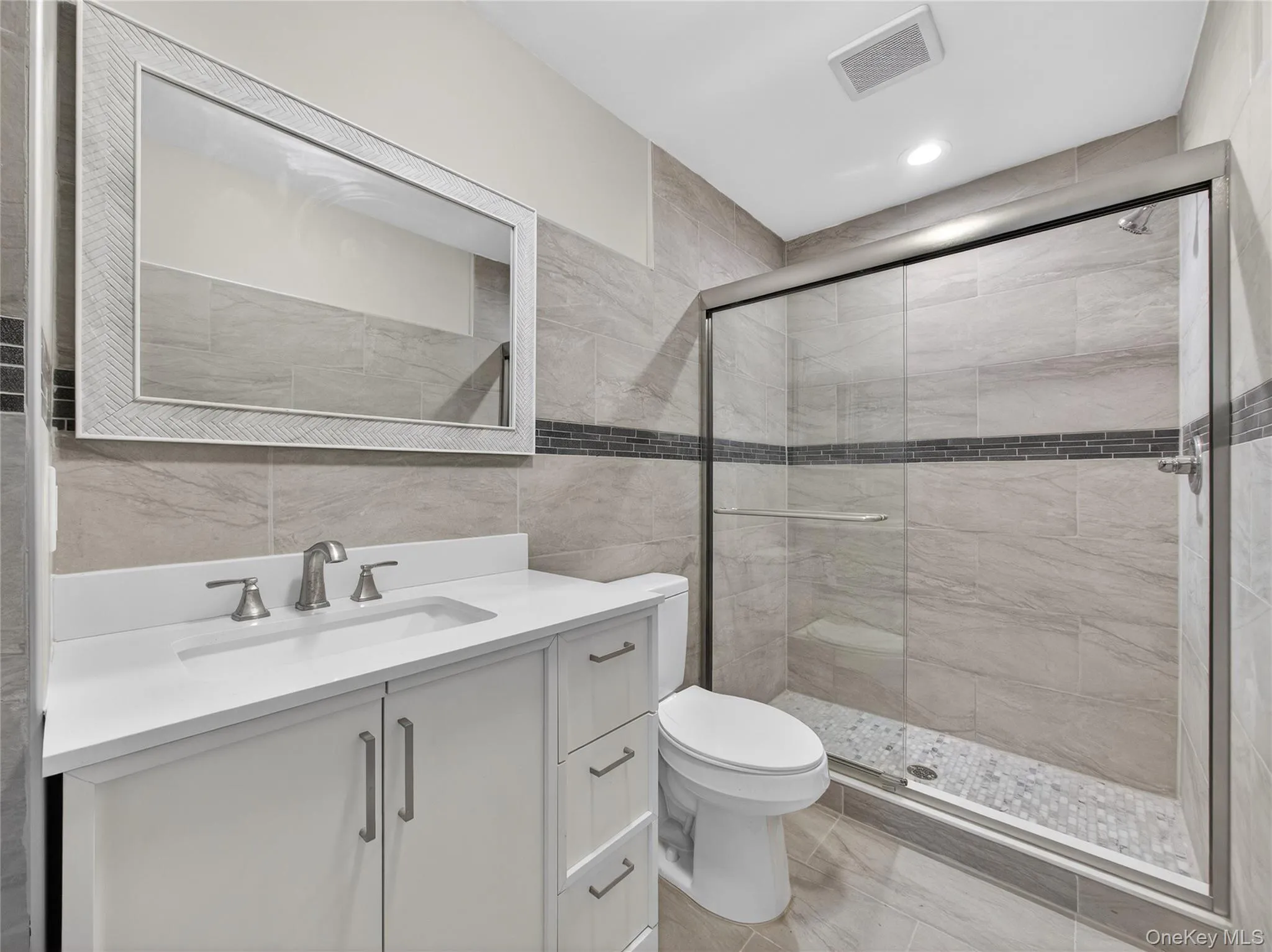 Bathroom featuring tile walls, vanity, a stall shower, and recessed lighting Bathroom featuring tile walls, vanity, a stall shower, and recessed lighting