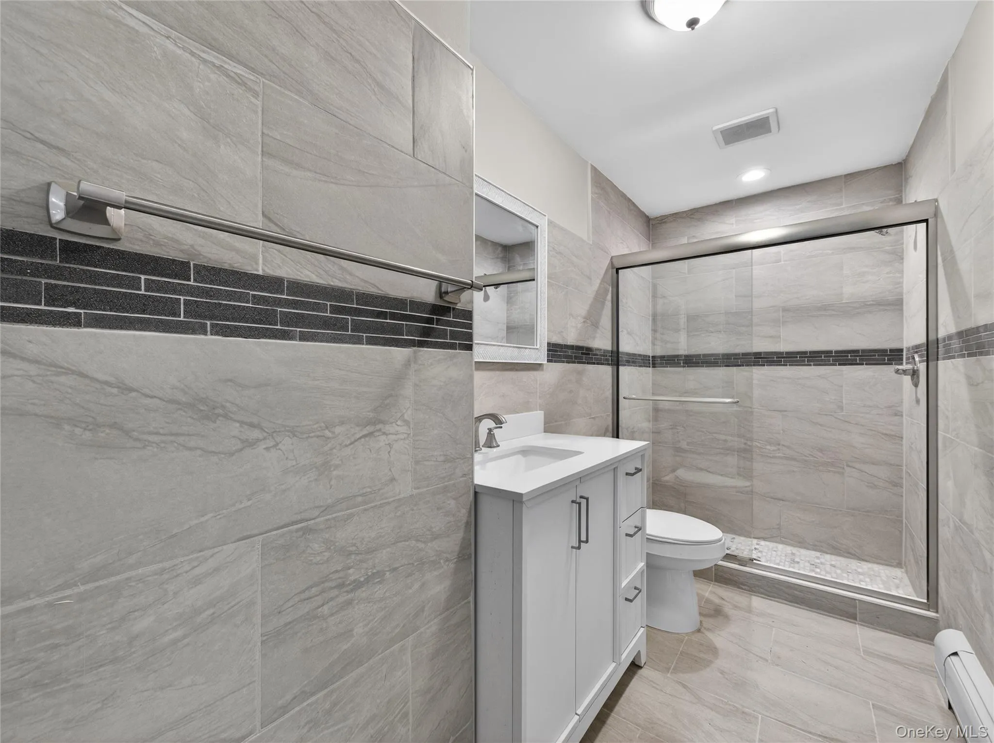 Full bathroom featuring vanity, baseboard heating, a stall shower, tile walls, and recessed lighting Full bathroom featuring vanity, baseboard heating, a stall shower, tile walls, and recessed lighting