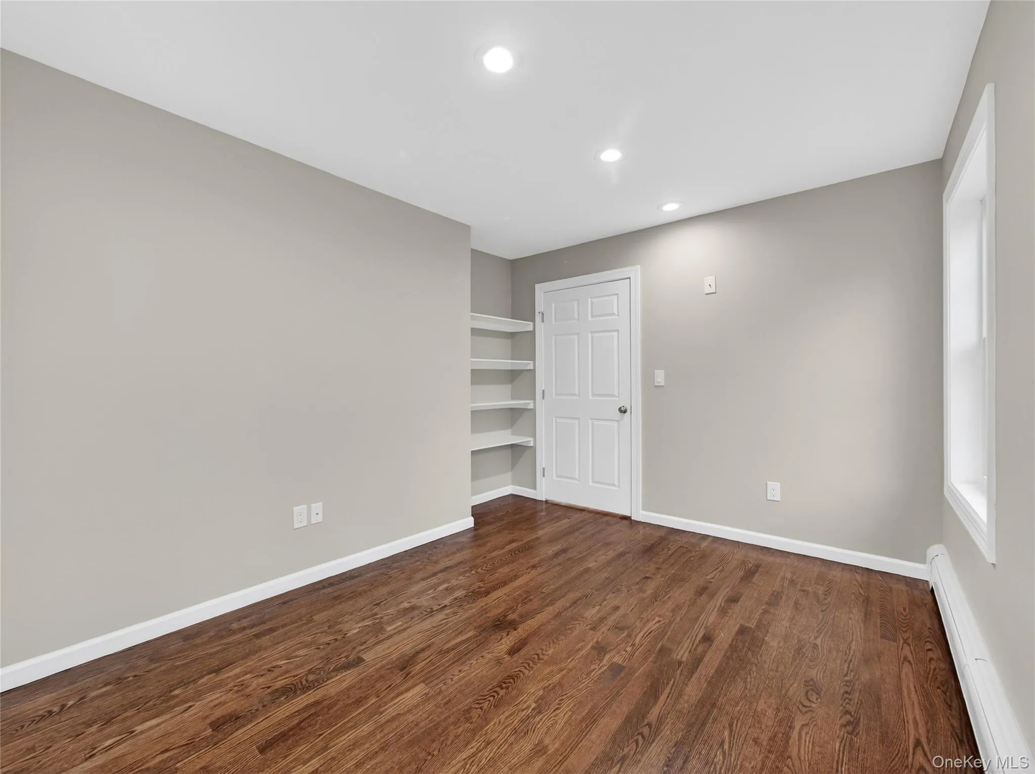 Spare room featuring baseboard heating, dark wood finished floors, recessed lighting, and built in features Spare room featuring baseboard heating, dark wood finished floors, recessed lighting, and built in features