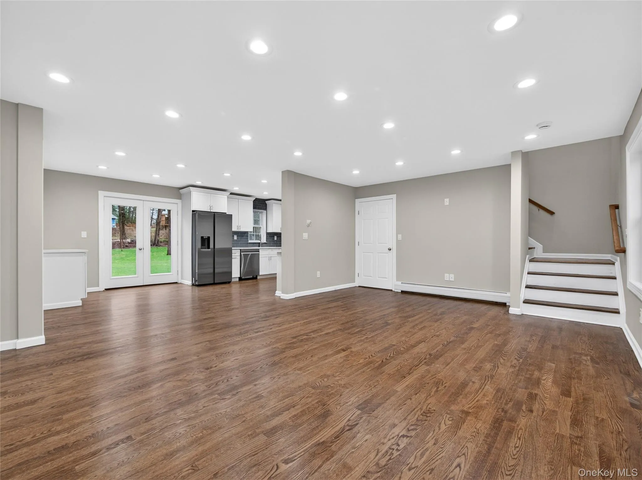 Unfurnished living room featuring recessed lighting, baseboard heating, and dark wood finished floors Unfurnished living room featuring recessed lighting, baseboard heating, and dark wood finished floors