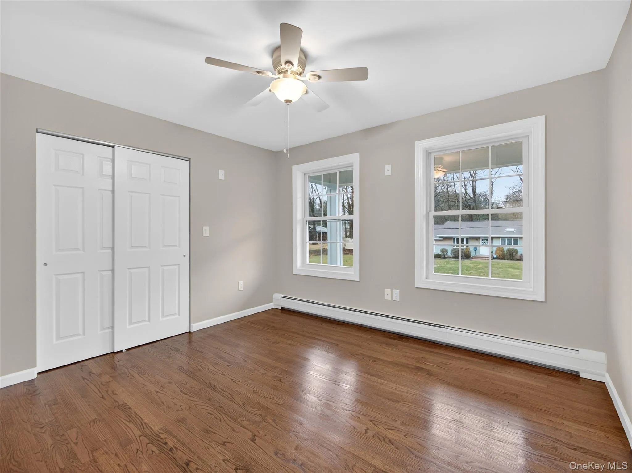 Unfurnished bedroom with baseboard heating, a closet, dark wood finished floors, and ceiling fan Unfurnished bedroom with baseboard heating, a closet, dark wood finished floors, and ceiling fan