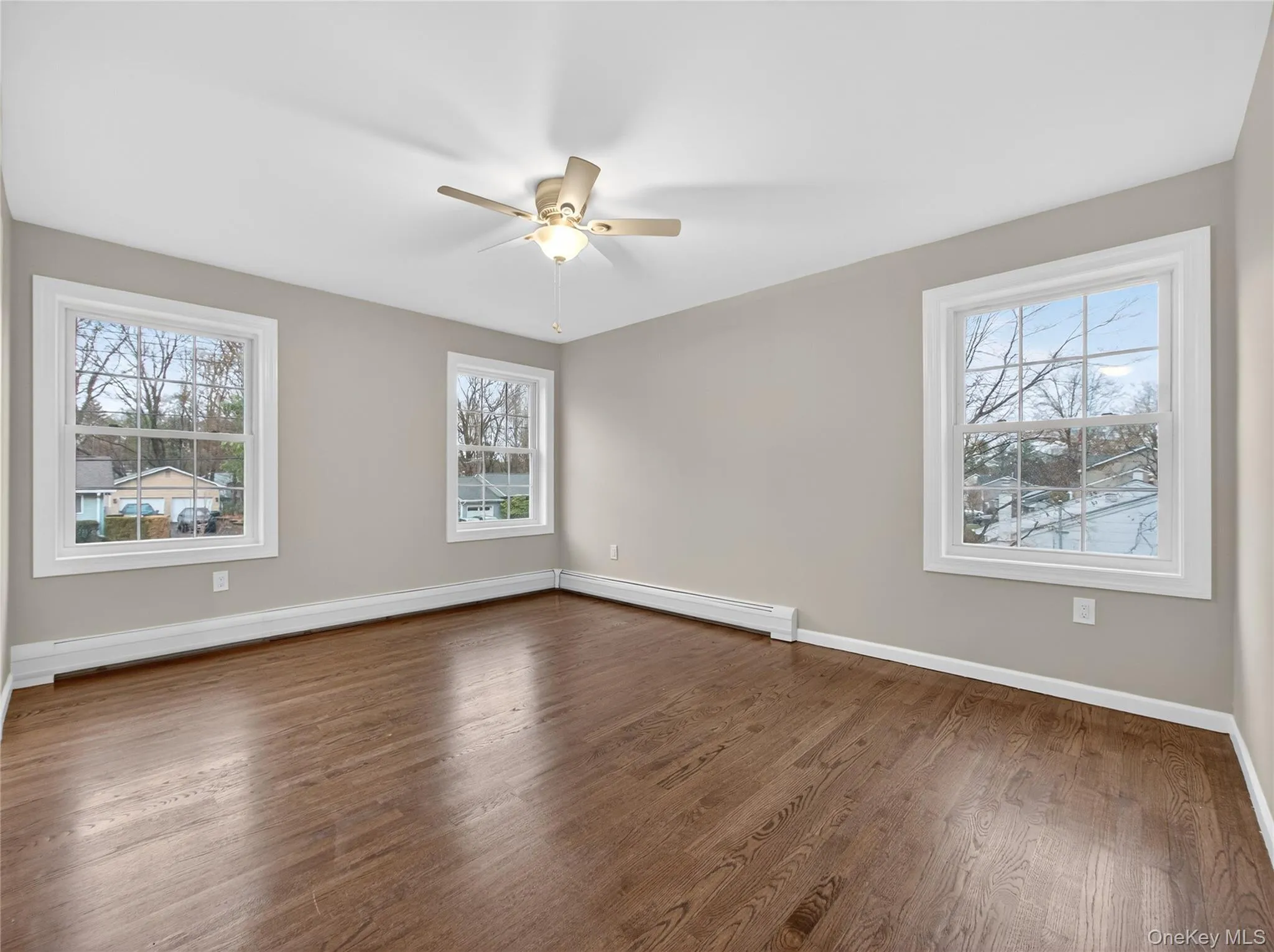 Spare room with dark wood-type flooring, a ceiling fan, and healthy amount of natural light Spare room with dark wood-type flooring, a ceiling fan, and healthy amount of natural light