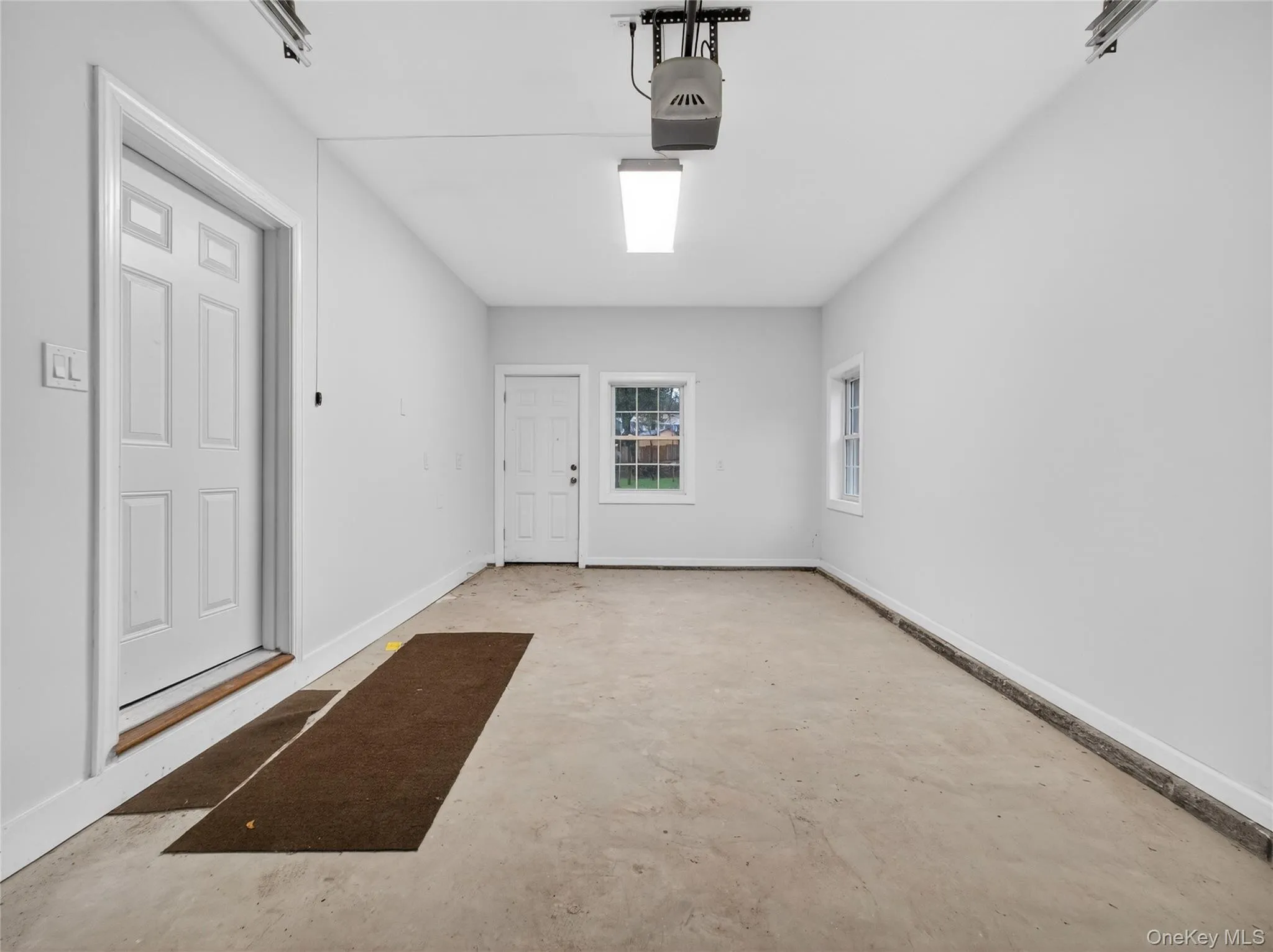 Garage featuring baseboards and a garage door opener Garage featuring baseboards and a garage door opener