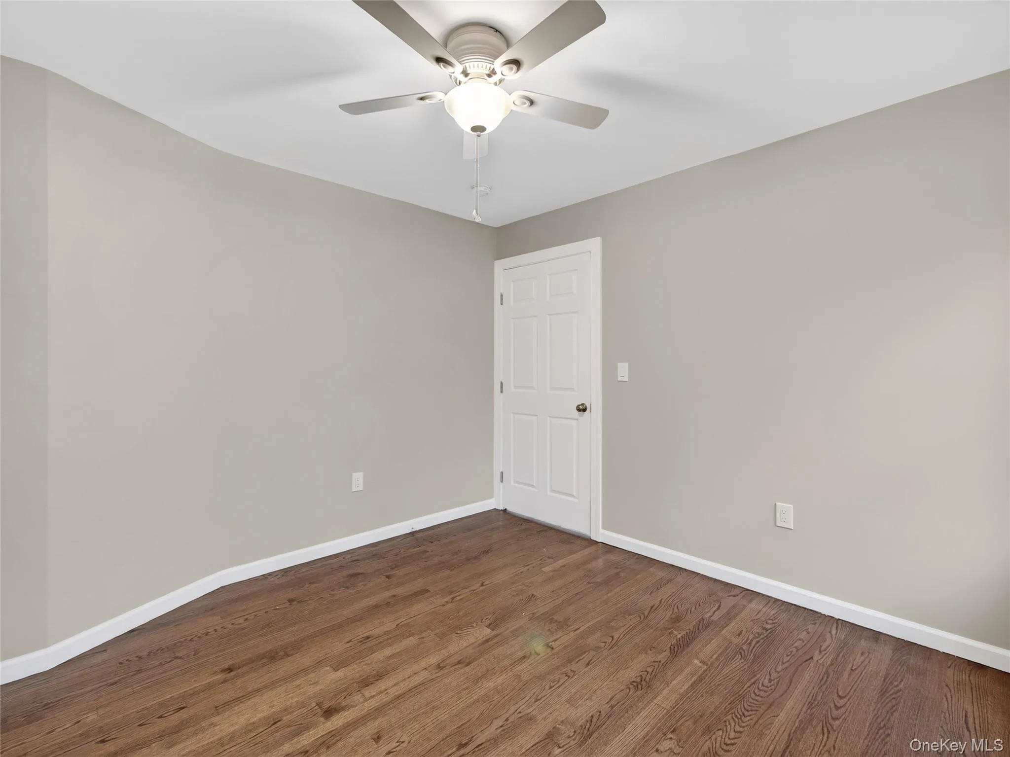 Empty room with dark wood-style floors and ceiling fan Empty room with dark wood-style floors and ceiling fan