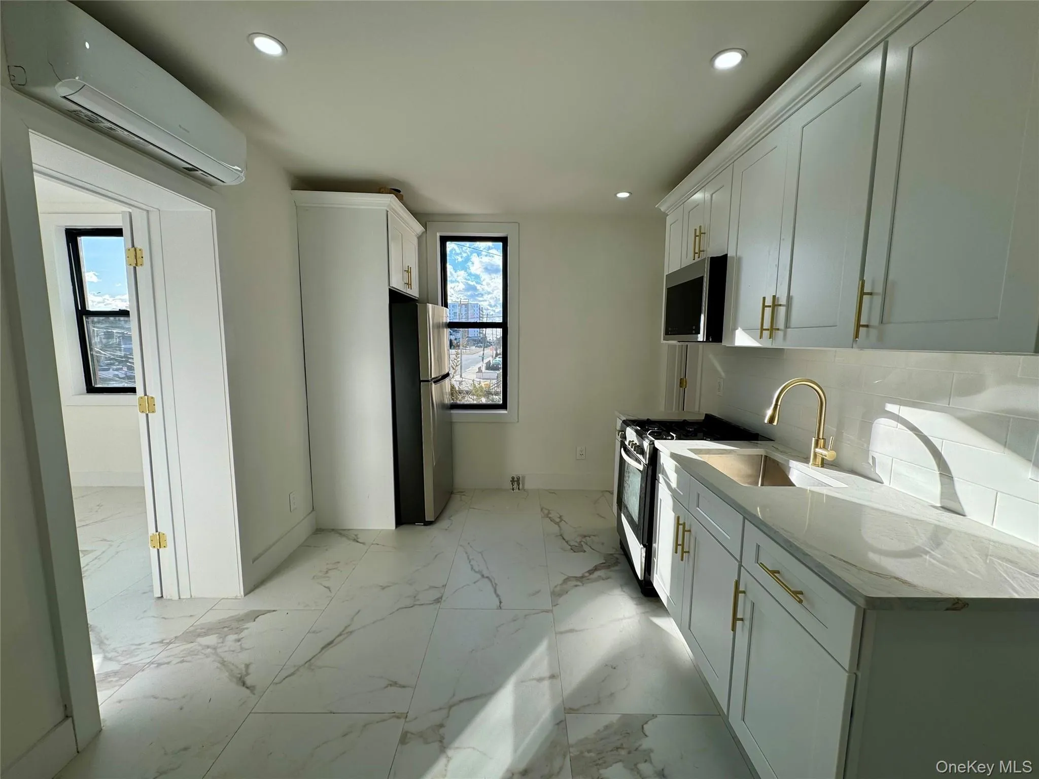 Kitchen with sink, stainless steel appliances, light stone counters, a wall unit AC, and backsplash Kitchen with sink, stainless steel appliances, light stone counters, a wall unit AC, and backsplash