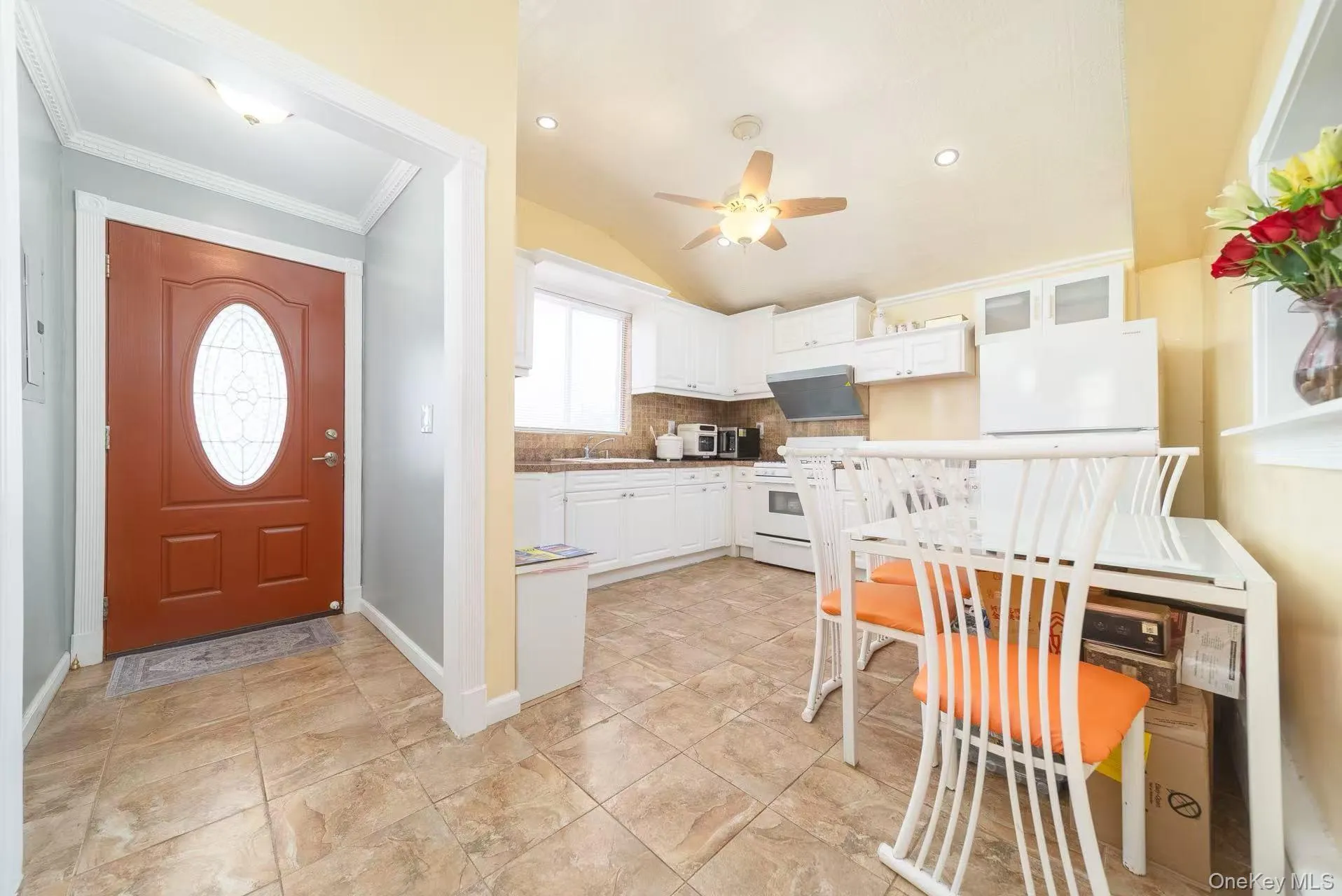 Kitchen with white cabinetry, white appliances, lofted ceiling, glass insert cabinets, and tasteful backsplash Kitchen with white cabinetry, white appliances, lofted ceiling, glass insert cabinets, and tasteful backsplash
