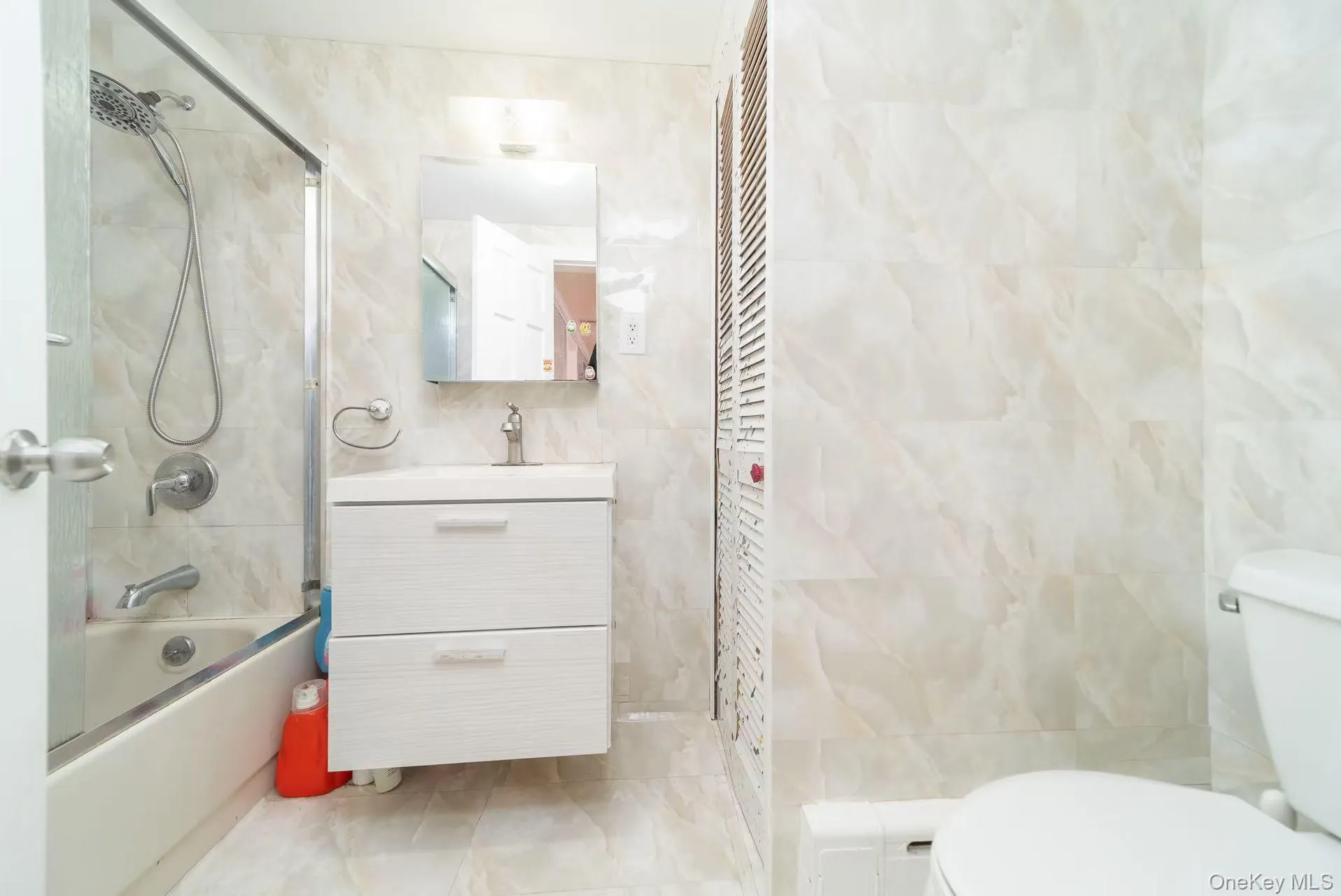 Bathroom featuring tile walls, vanity, and enclosed tub / shower combo Bathroom featuring tile walls, vanity, and enclosed tub / shower combo