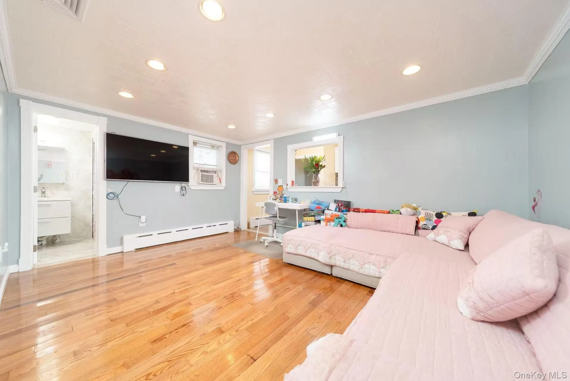 Bedroom with ornamental molding, light wood-style floors, baseboard heating, recessed lighting, and cooling unit Bedroom with ornamental molding, light wood-style floors, baseboard heating, recessed lighting, and cooling unit