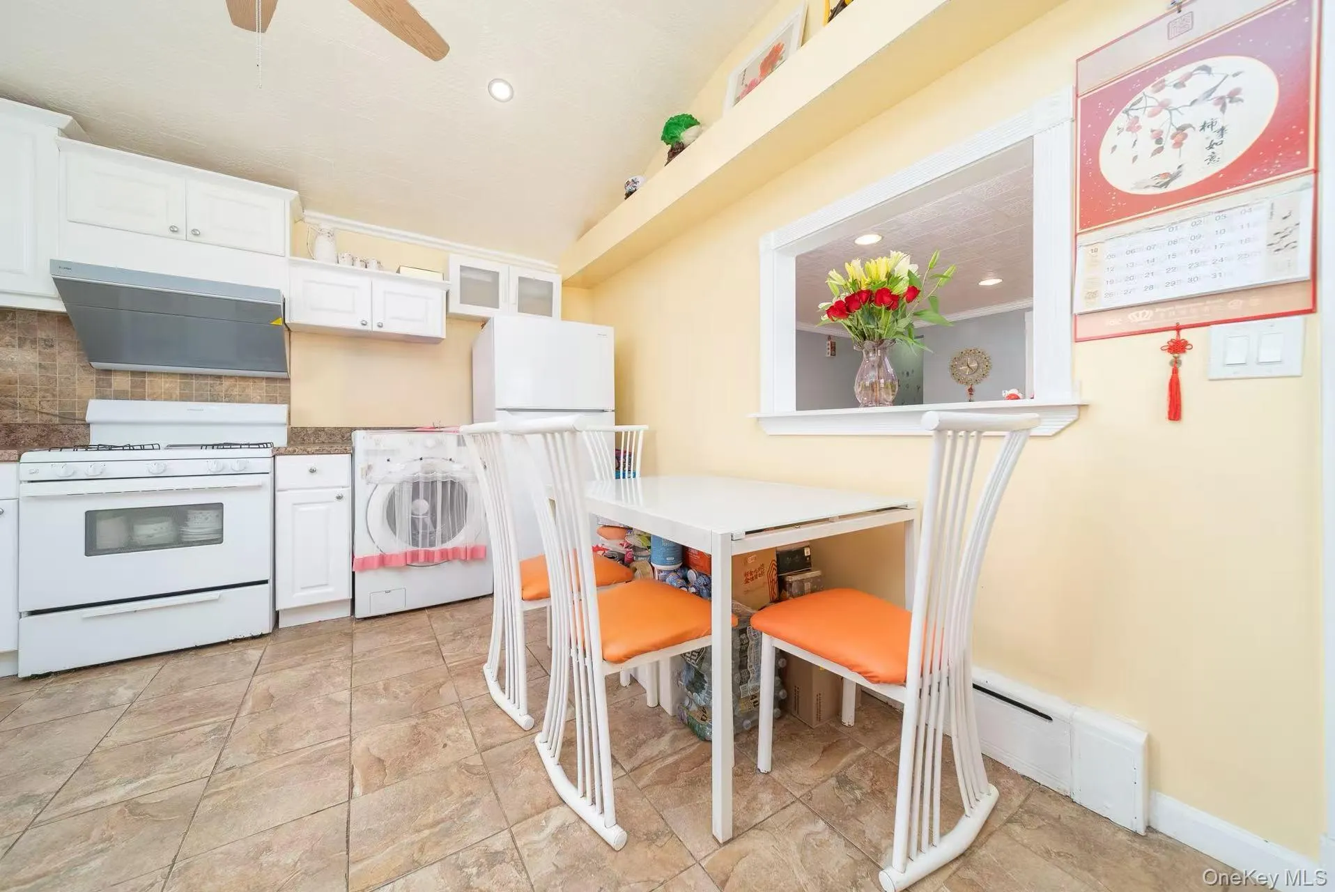 Kitchen featuring white cabinets, white appliances, washer / dryer, range hood, and recessed lighting Kitchen featuring white cabinets, white appliances, washer / dryer, range hood, and recessed lighting
