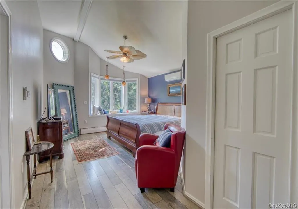 Recessed wood-finish flooring, bay window with integrated seating, vaulted ceiling with exposed beams, oval accent window, and a ceiling fan with integrated lighting Recessed wood-finish flooring, bay window with integrated seating, vaulted ceiling with exposed beams, oval accent window, and a ceiling fan with integrated lighting