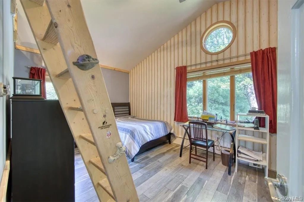 Vaulted ceiling with vertical plank wall finish, wood-finish flooring, and a round window Vaulted ceiling with vertical plank wall finish, wood-finish flooring, and a round window