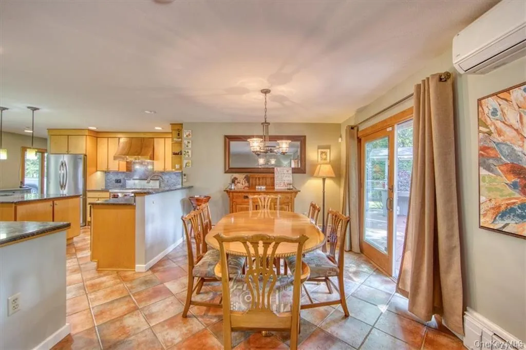 Open-concept living area with tile flooring, wood-finish cabinetry, stainless steel appliances, and a glass sliding door Open-concept living area with tile flooring, wood-finish cabinetry, stainless steel appliances, and a glass sliding door