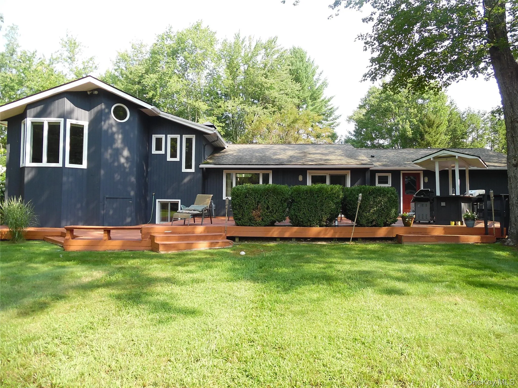 Expansive rear deck with multiple levels, privacy hedging, and white-trimmed windows Expansive rear deck with multiple levels, privacy hedging, and white-trimmed windows