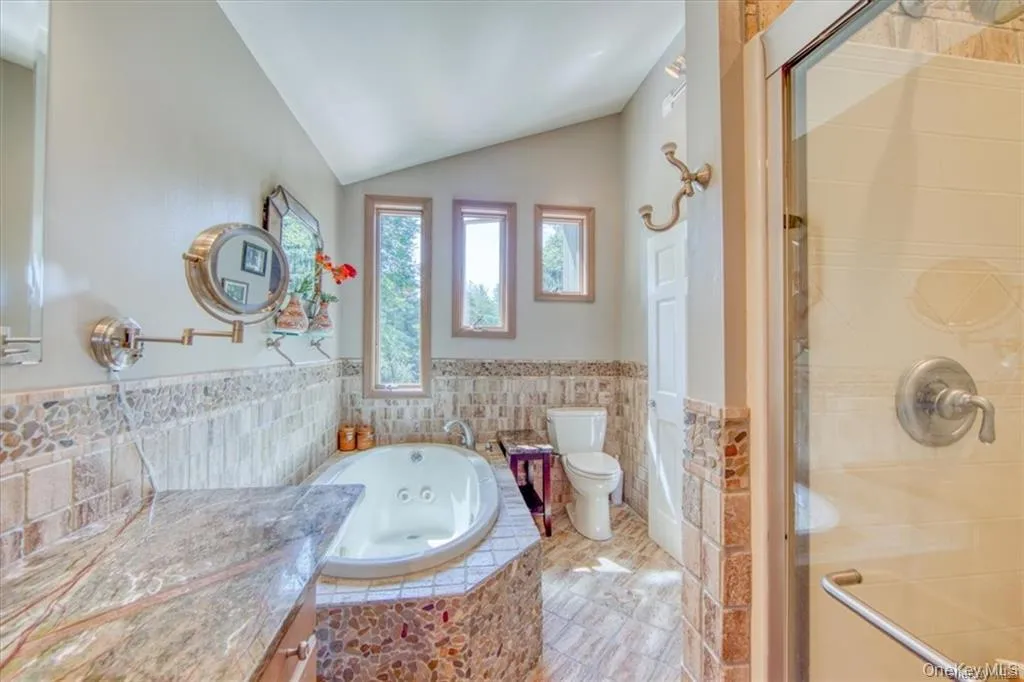 Soaking tub with stone surround, natural stone tile accents, and a granite-finish vanity countertop Soaking tub with stone surround, natural stone tile accents, and a granite-finish vanity countertop