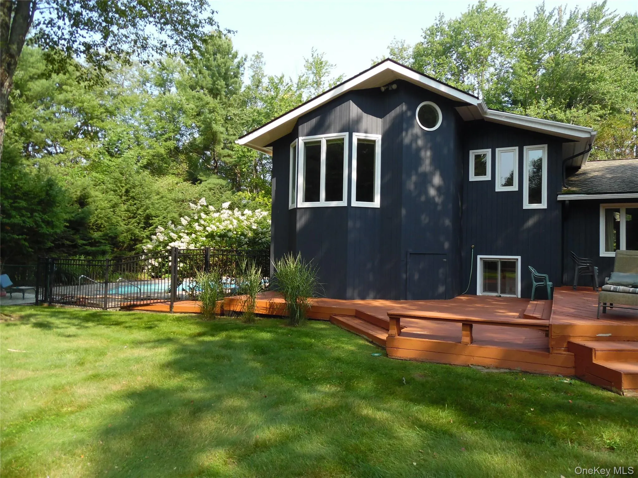 Expansive multi-level wood deck, dark-toned vertical siding, and a fenced swimming pool Expansive multi-level wood deck, dark-toned vertical siding, and a fenced swimming pool