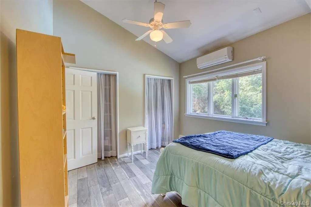 Vaulted ceiling with a ceiling fan, wood-finish flooring, white paneled door, and a built-in air conditioning unit Vaulted ceiling with a ceiling fan, wood-finish flooring, white paneled door, and a built-in air conditioning unit