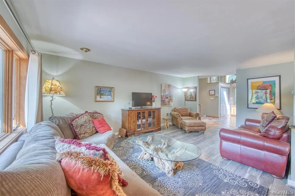 Spacious living area featuring wood-finish flooring, recessed lighting, and a large window with wood trim Spacious living area featuring wood-finish flooring, recessed lighting, and a large window with wood trim