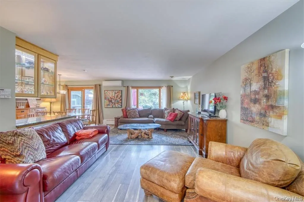 Open-concept living area with wood-finish flooring, recessed lighting, and a built-in display cabinet with glass doors Open-concept living area with wood-finish flooring, recessed lighting, and a built-in display cabinet with glass doors