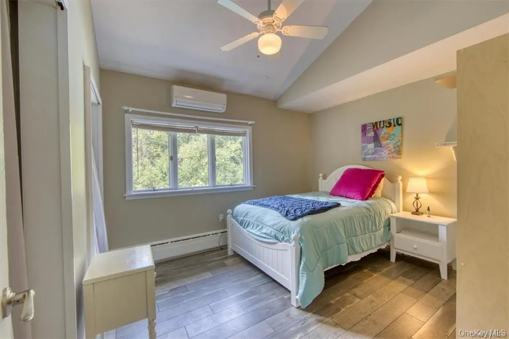 Wood-finish flooring, vaulted ceiling, built-in window, and wall-mounted climate control unit Wood-finish flooring, vaulted ceiling, built-in window, and wall-mounted climate control unit