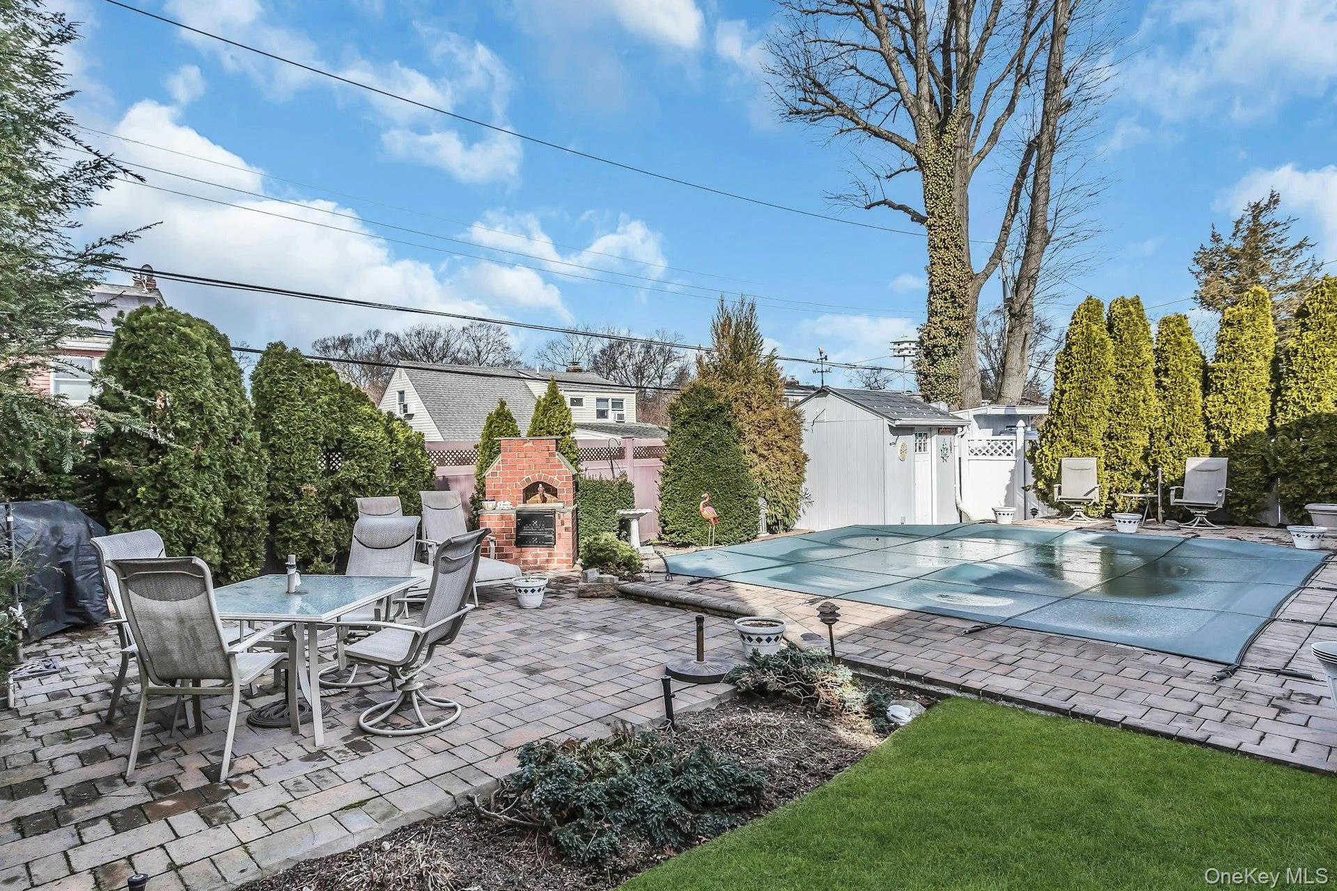 View of pool featuring an outdoor brick fireplace, patio surround, outdoor dining space, and a fenced backyard View of pool featuring an outdoor brick fireplace, patio surround, outdoor dining space, and a fenced backyard