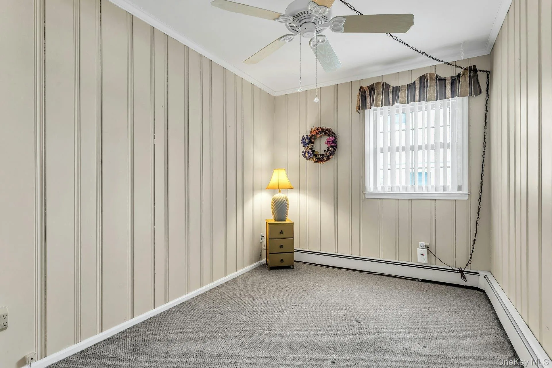 Spare room featuring baseboard heating, crown molding, ceiling fan, and carpet floors Spare room featuring baseboard heating, crown molding, ceiling fan, and carpet floors