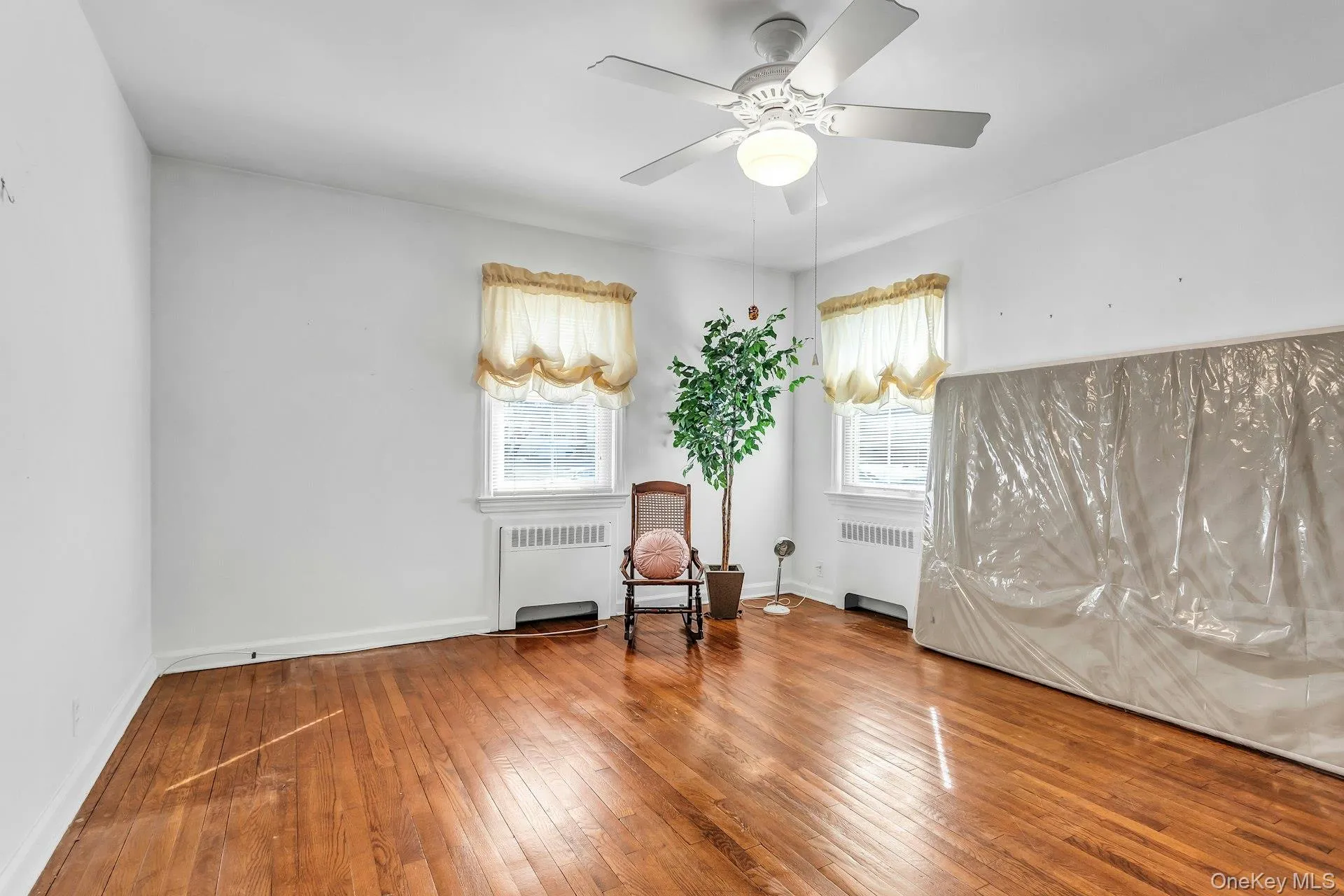 Primary Bedroom featuring radiator heating unit, hardwood / wood-style floors, and ceiling fan Primary Bedroom featuring radiator heating unit, hardwood / wood-style floors, and ceiling fan