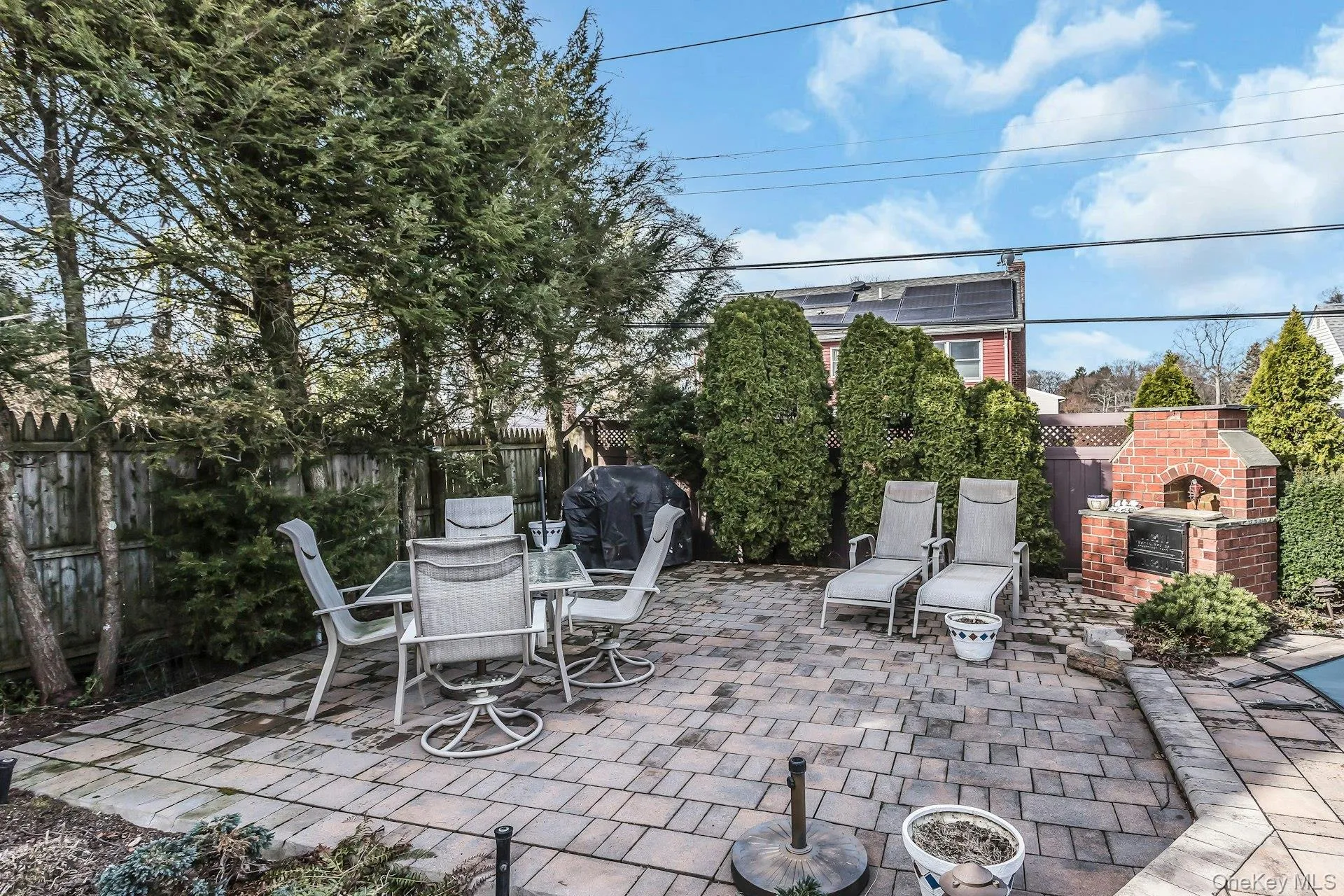 Fenced backyard with an outdoor brick fireplace, a patio area, outdoor dining area, and area for grilling Fenced backyard with an outdoor brick fireplace, a patio area, outdoor dining area, and area for grilling