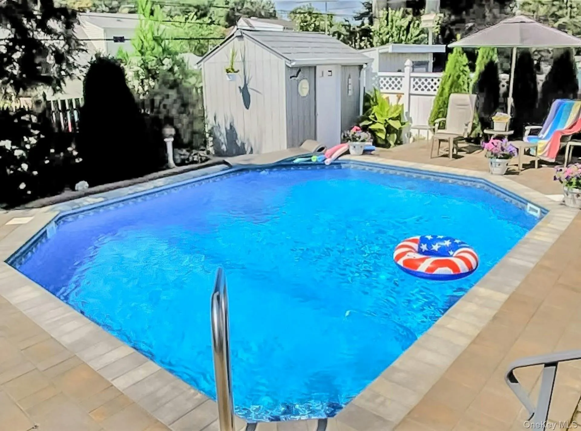View of pool featuring a storage shed, a fenced backyard, and patio surround View of pool featuring a storage shed, a fenced backyard, and patio surround