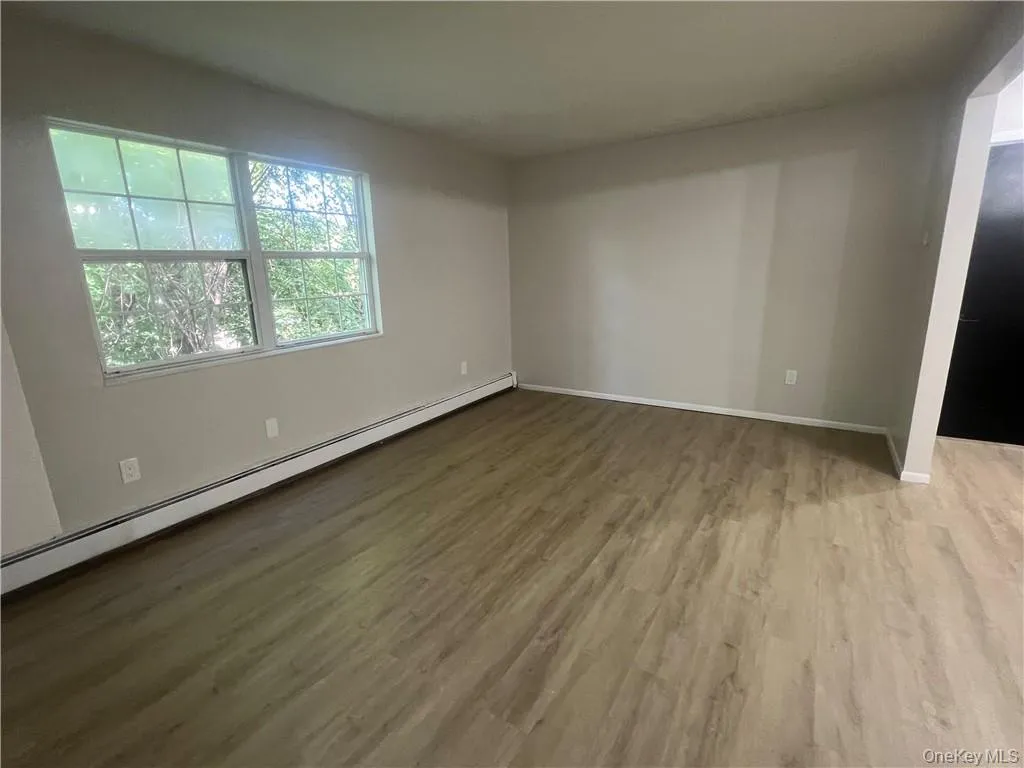 Spare room featuring baseboard heating and wood-type flooring Spare room featuring baseboard heating and wood-type flooring