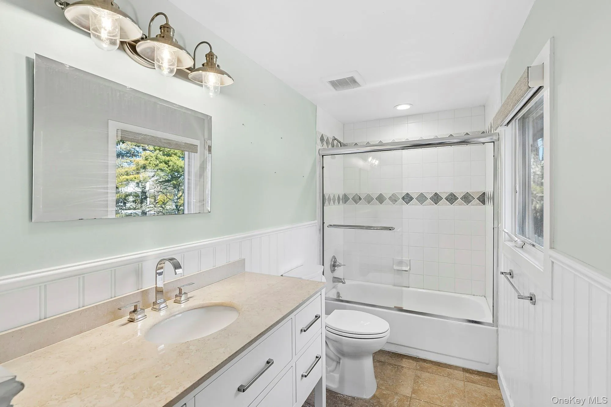 Full bathroom with a bathtub and decorative tile accents set within white wall tile. Full bathroom with a bathtub and decorative tile accents set within white wall tile.