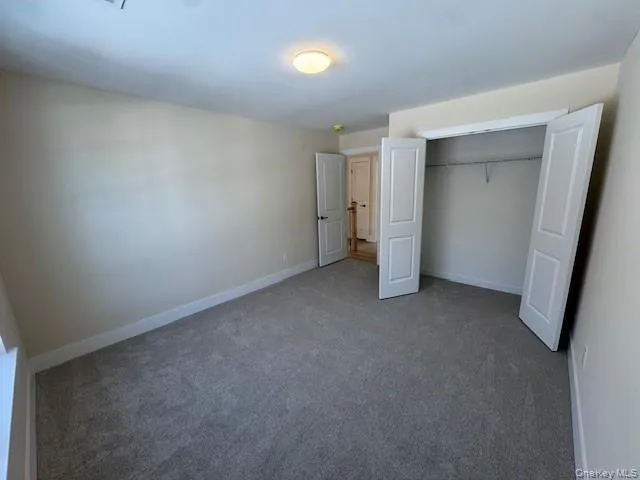 Unfurnished bedroom featuring carpet flooring and a large closet Unfurnished bedroom featuring carpet flooring and a large closet