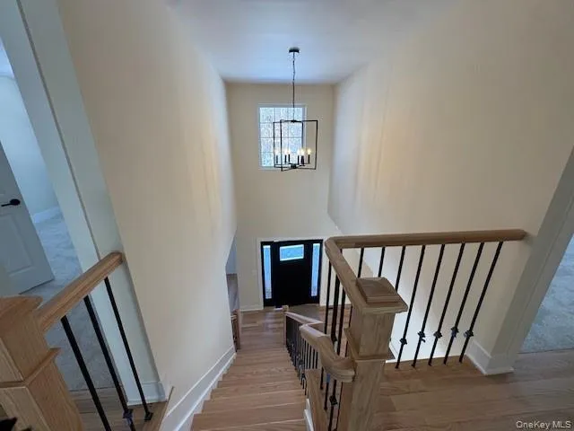 Stairway with suspended lighting, wood finished floors, and a high ceiling Stairway with suspended lighting, wood finished floors, and a high ceiling
