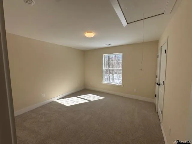 Empty room featuring light carpet and attic access Empty room featuring light carpet and attic access