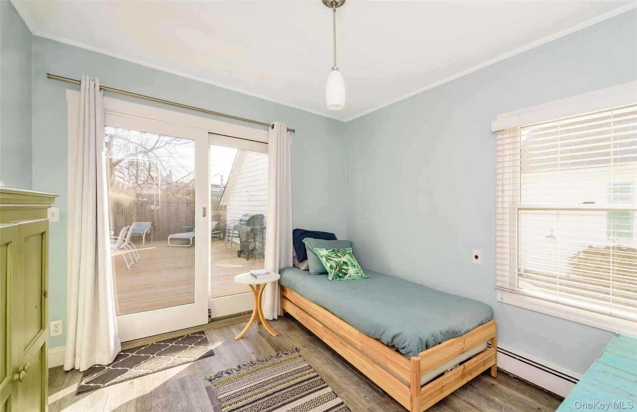 Bedroom with dark hardwood / wood-style floors, ornamental molding, access to outside, and a baseboard heating unit Bedroom with dark hardwood / wood-style floors, ornamental molding, access to outside, and a baseboard heating unit