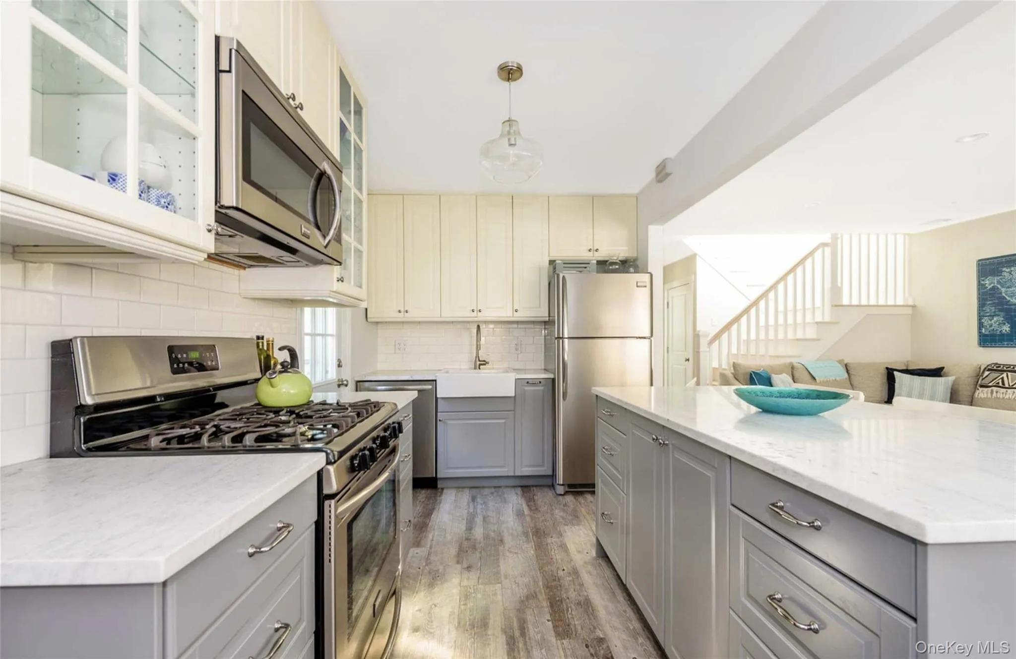 Kitchen with gray cabinetry, pendant lighting, sink, wood-type flooring, and stainless steel appliances Kitchen with gray cabinetry, pendant lighting, sink, wood-type flooring, and stainless steel appliances
