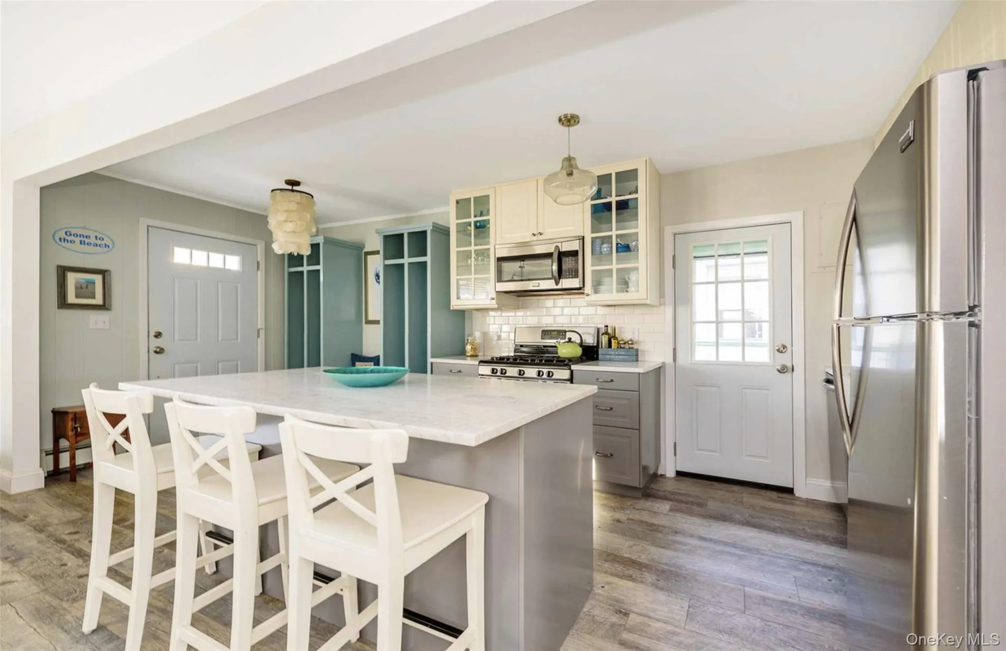 Kitchen featuring pendant lighting, a center island, light stone countertops, appliances with stainless steel finishes, and wood-type flooring Kitchen featuring pendant lighting, a center island, light stone countertops, appliances with stainless steel finishes, and wood-type flooring