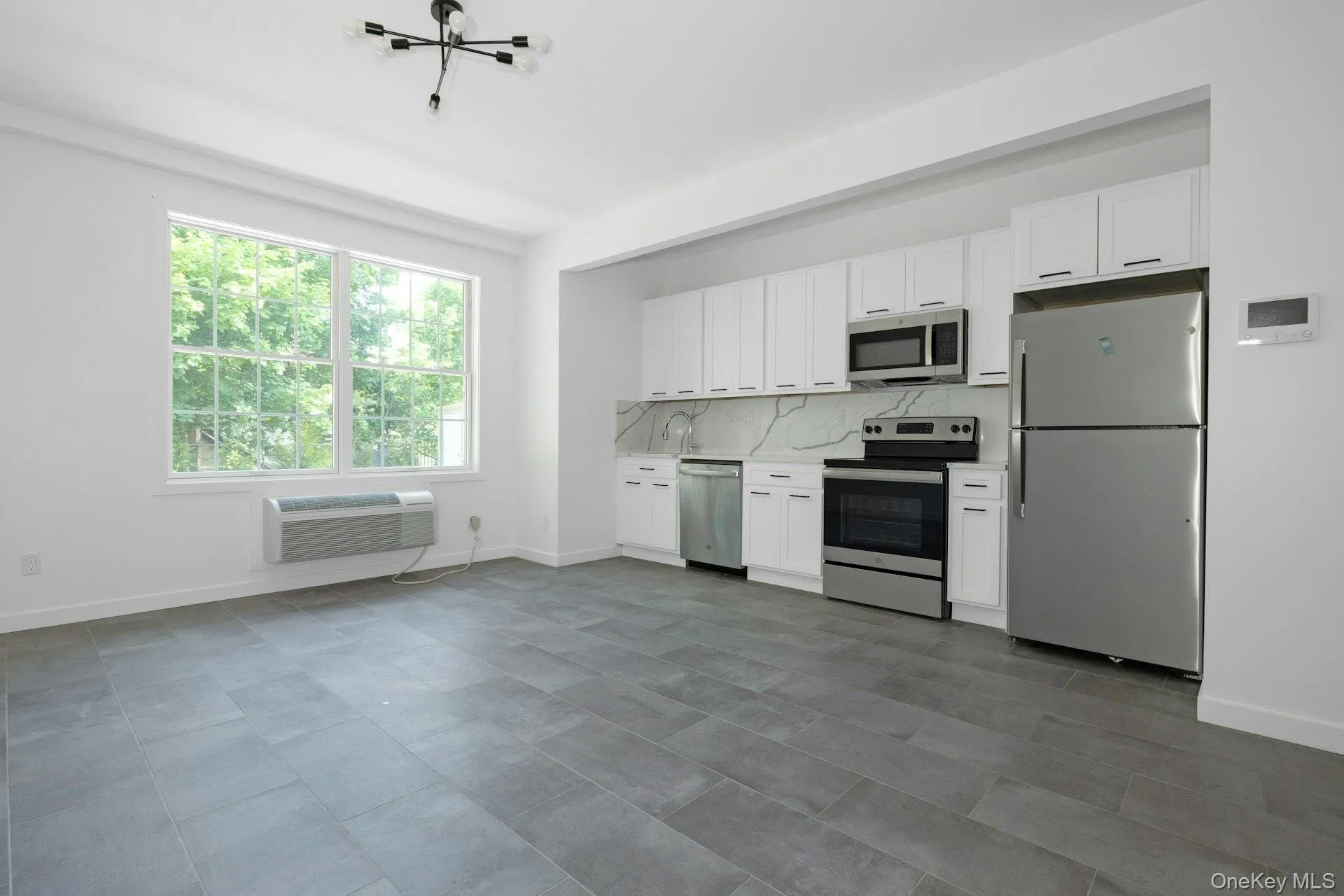 Kitchen featuring white cabinets, stainless steel appliances, stone countertop and tasteful backsplash. Kitchen featuring white cabinets, stainless steel appliances, stone countertop and tasteful backsplash.