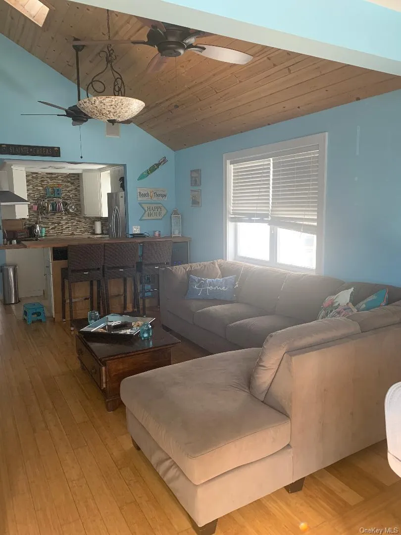 Living room with a ceiling fan, lofted ceiling, wood ceiling, and light wood-style floors Living room with a ceiling fan, lofted ceiling, wood ceiling, and light wood-style floors