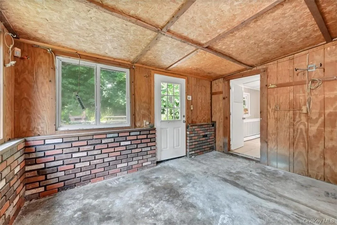 Spare room featuring concrete floors, lofted ceiling, wooden walls, and a baseboard radiator Spare room featuring concrete floors, lofted ceiling, wooden walls, and a baseboard radiator