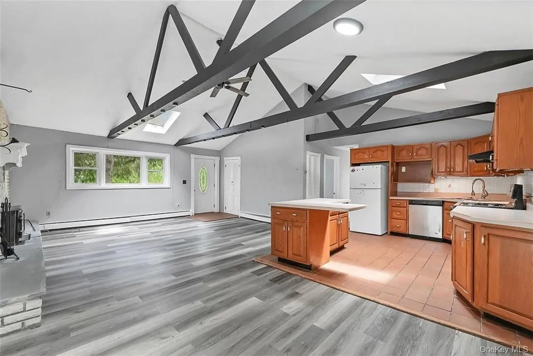 Kitchen featuring stainless steel dishwasher, a skylight, white refrigerator, and beam ceiling Kitchen featuring stainless steel dishwasher, a skylight, white refrigerator, and beam ceiling