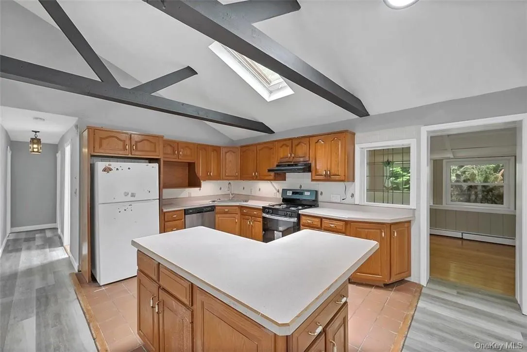 Kitchen with light hardwood / wood-style floors, lofted ceiling with skylight, white refrigerator, and gas range Kitchen with light hardwood / wood-style floors, lofted ceiling with skylight, white refrigerator, and gas range