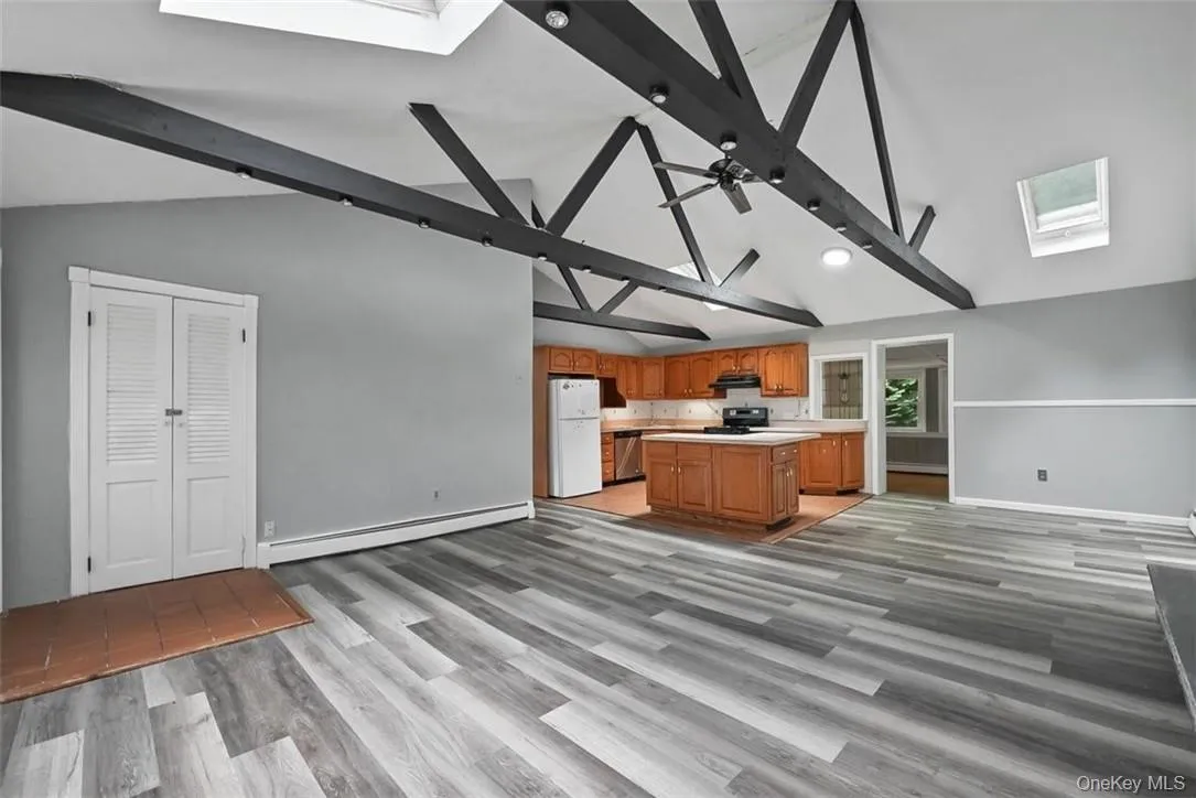 Kitchen with beamed ceiling, light hardwood / wood-style flooring, white refrigerator, a skylight, and baseboard heating Kitchen with beamed ceiling, light hardwood / wood-style flooring, white refrigerator, a skylight, and baseboard heating