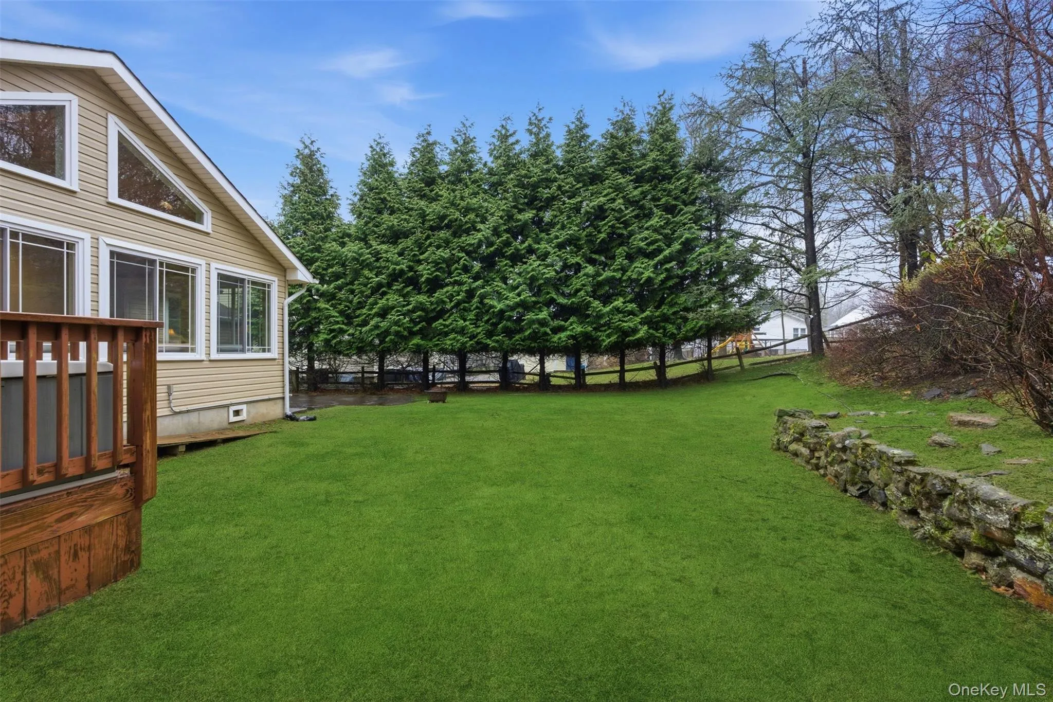 View of backyard yard with rock wall. View of backyard yard with rock wall.