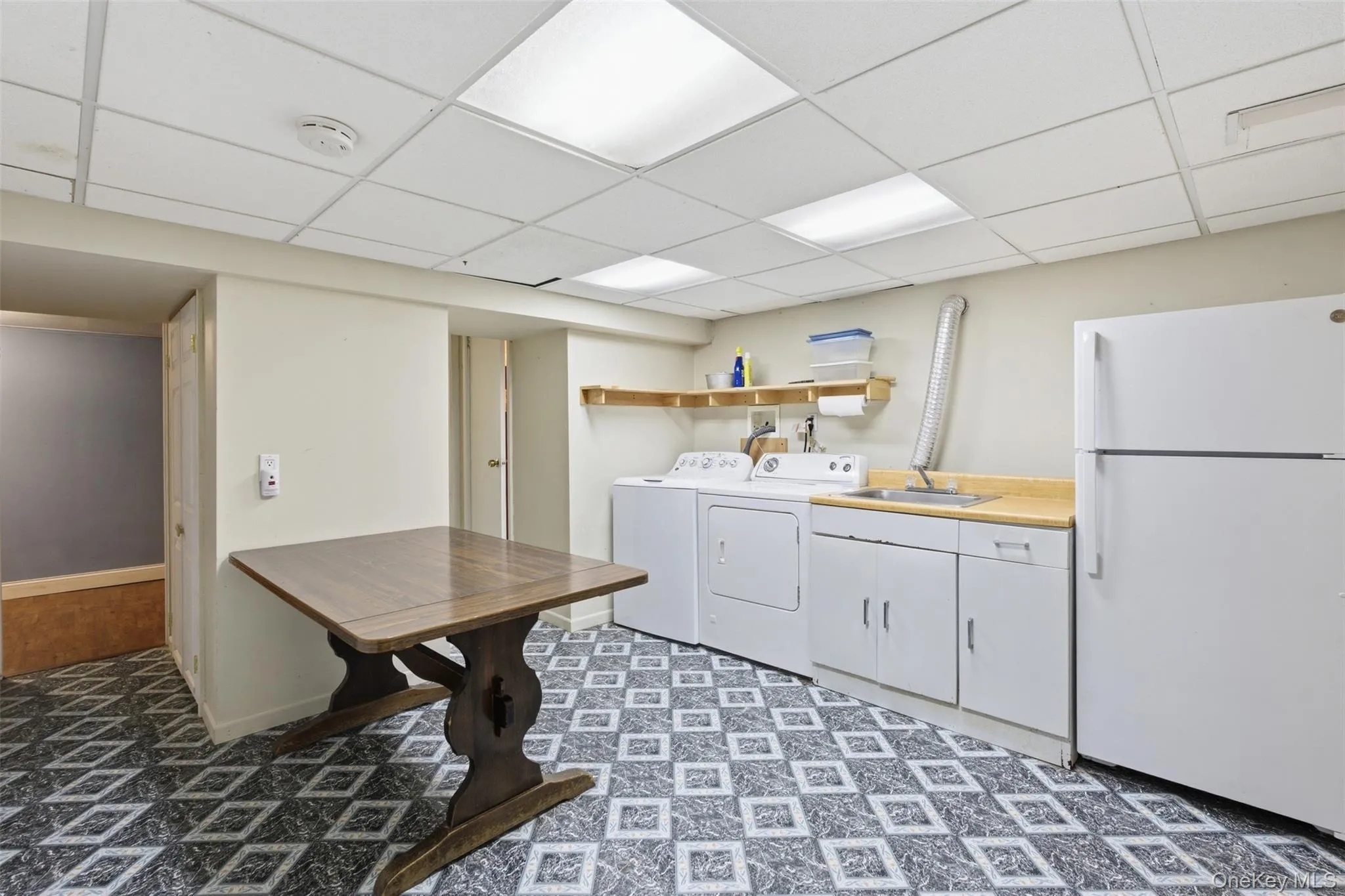 Laundry area with washer and clothes dryer, a drop ceiling, light floors, and cabinet space Laundry area with washer and clothes dryer, a drop ceiling, light floors, and cabinet space