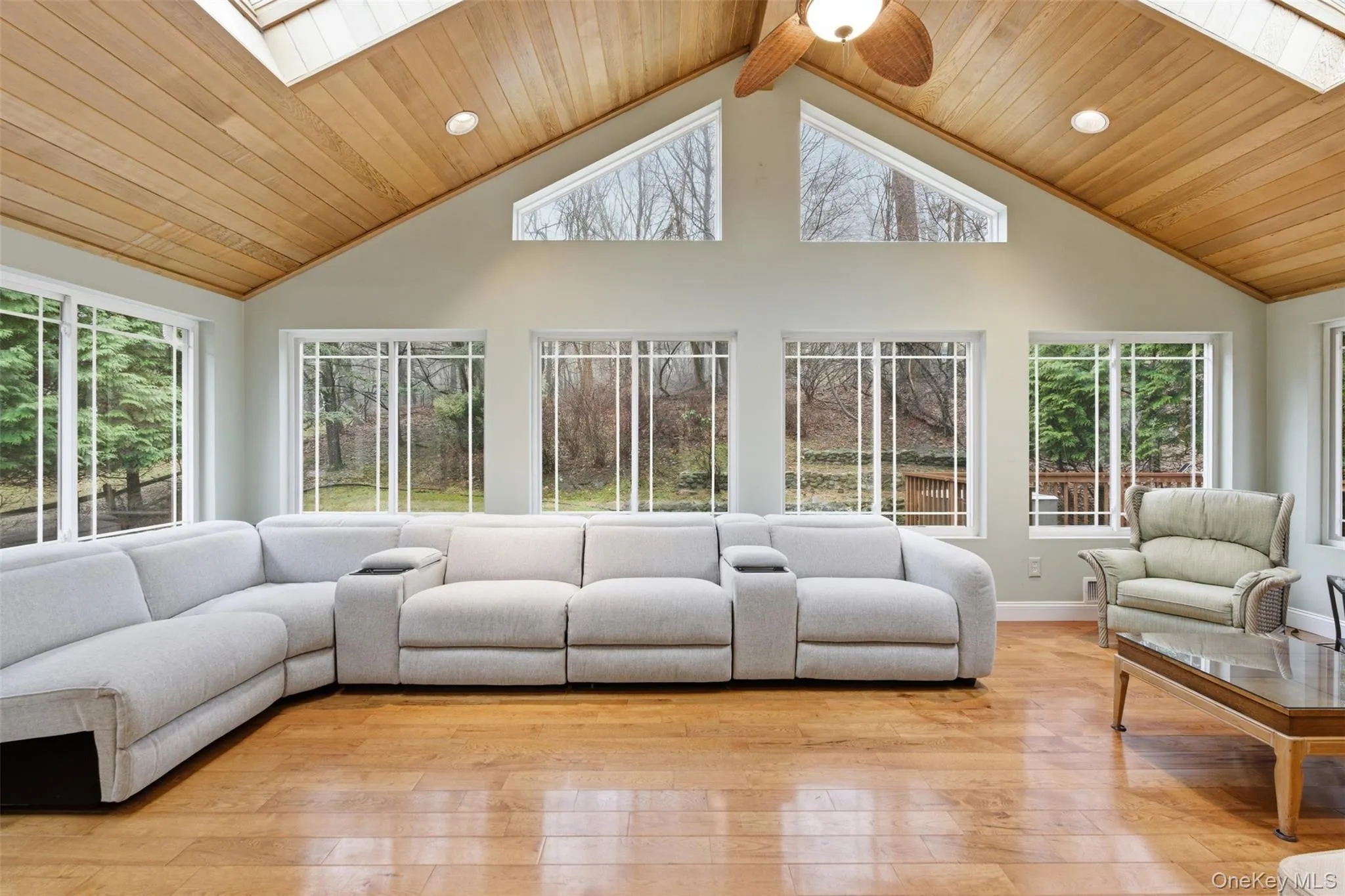 Living area with a skylight, a high wood ceiling, light wood-type flooring, and ceiling fan Living area with a skylight, a high wood ceiling, light wood-type flooring, and ceiling fan